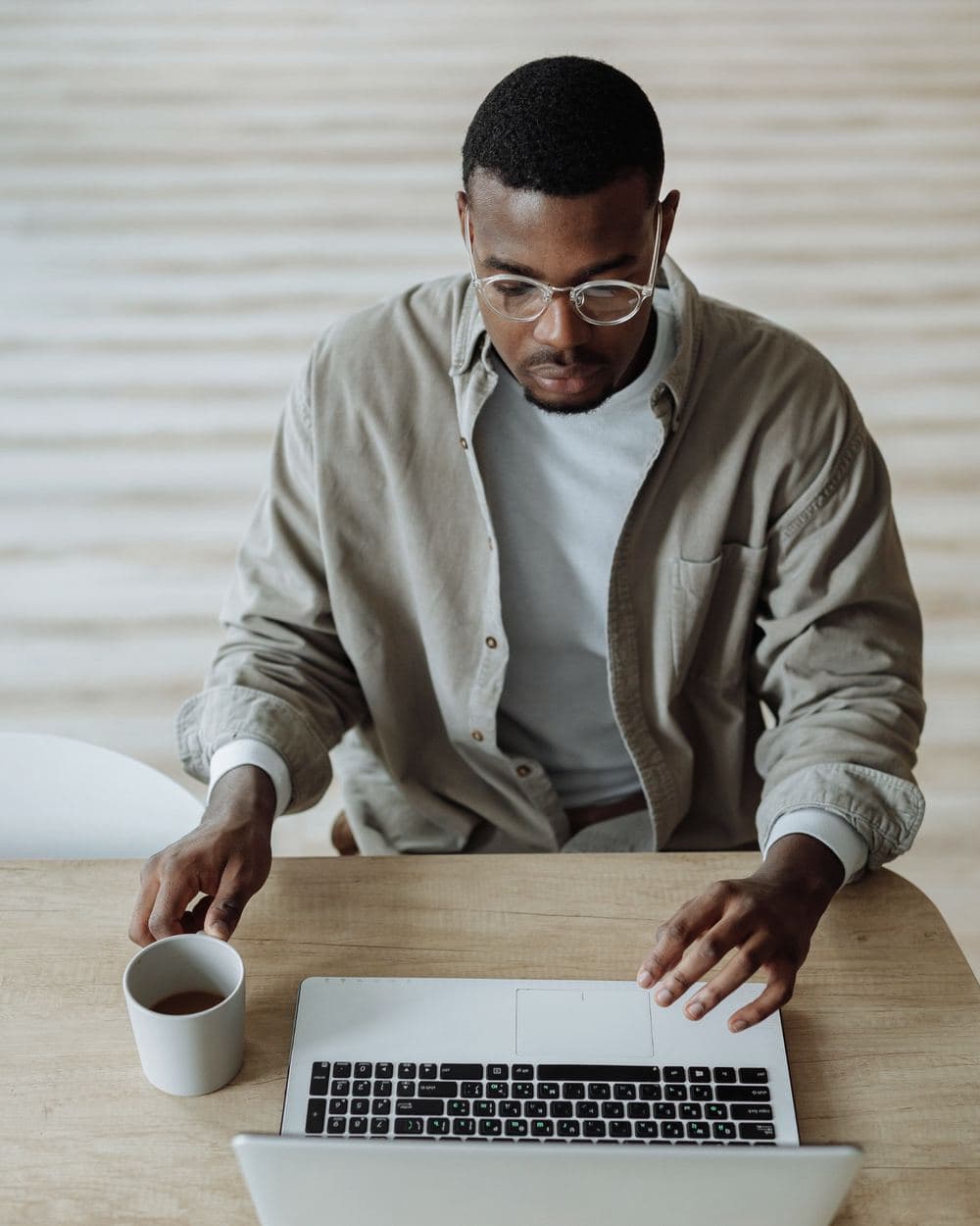 Profissional trabalhando no notebook com uma xícara de café na mesa.